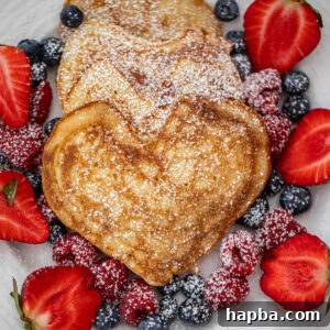 Heart shaped pancakes on a plate with fresh berries, ready to be served for a special breakfast or brunch occasion. The pancakes are fluffy and golden.