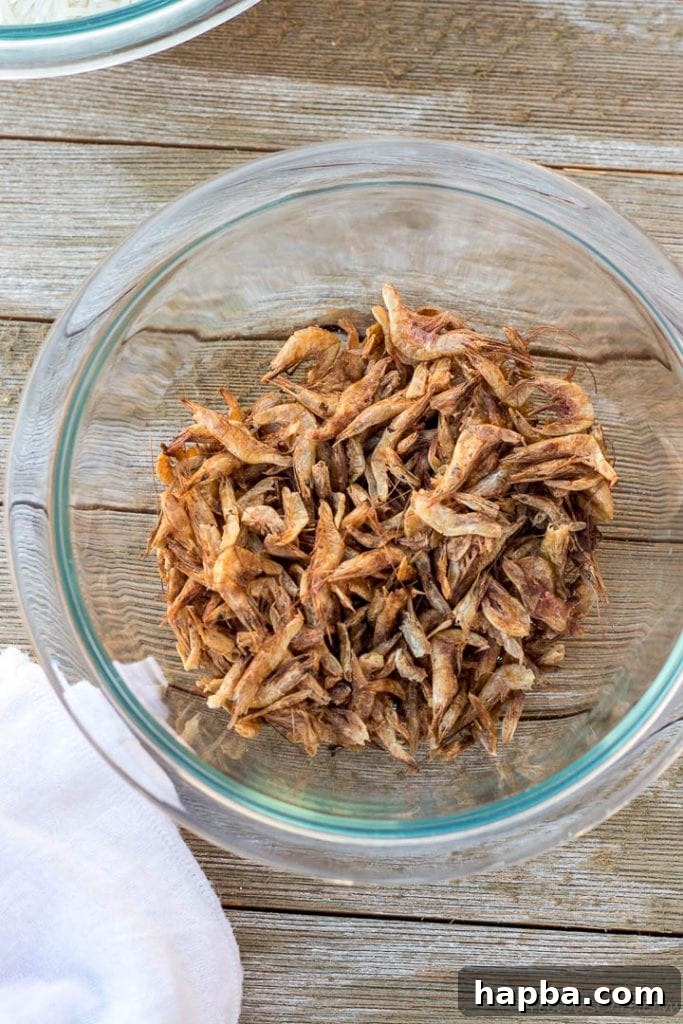 A close-up shot of dried crayfish in a rustic wooden bowl, ready for cooking.