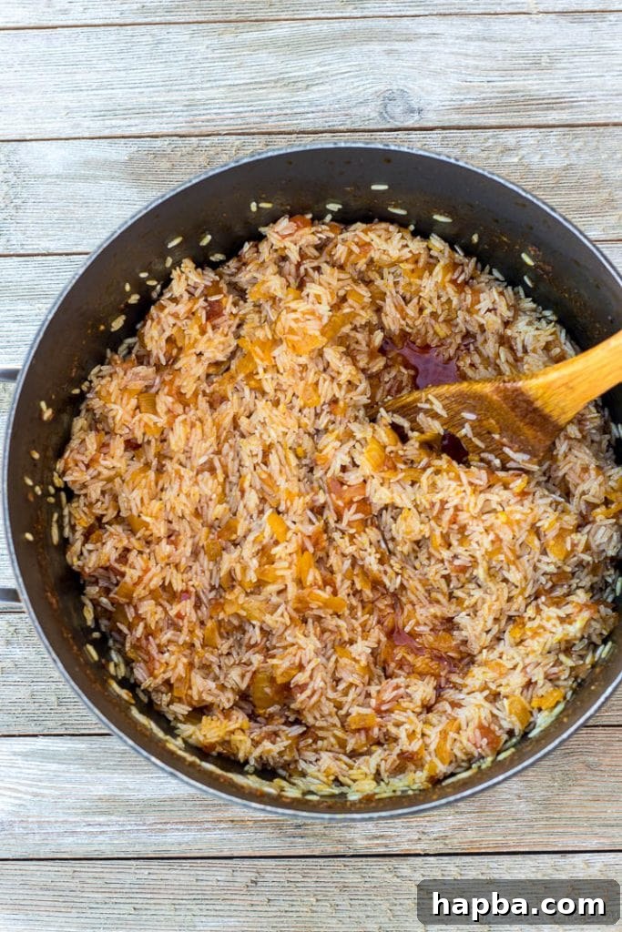 Washed rice added to the palm oil and tomato sauce in a pot, stirred evenly.