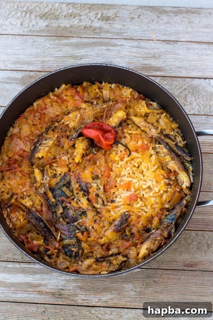 Just cooked palm oil jollof rice, still covered in the pot, revealing its vibrant color.