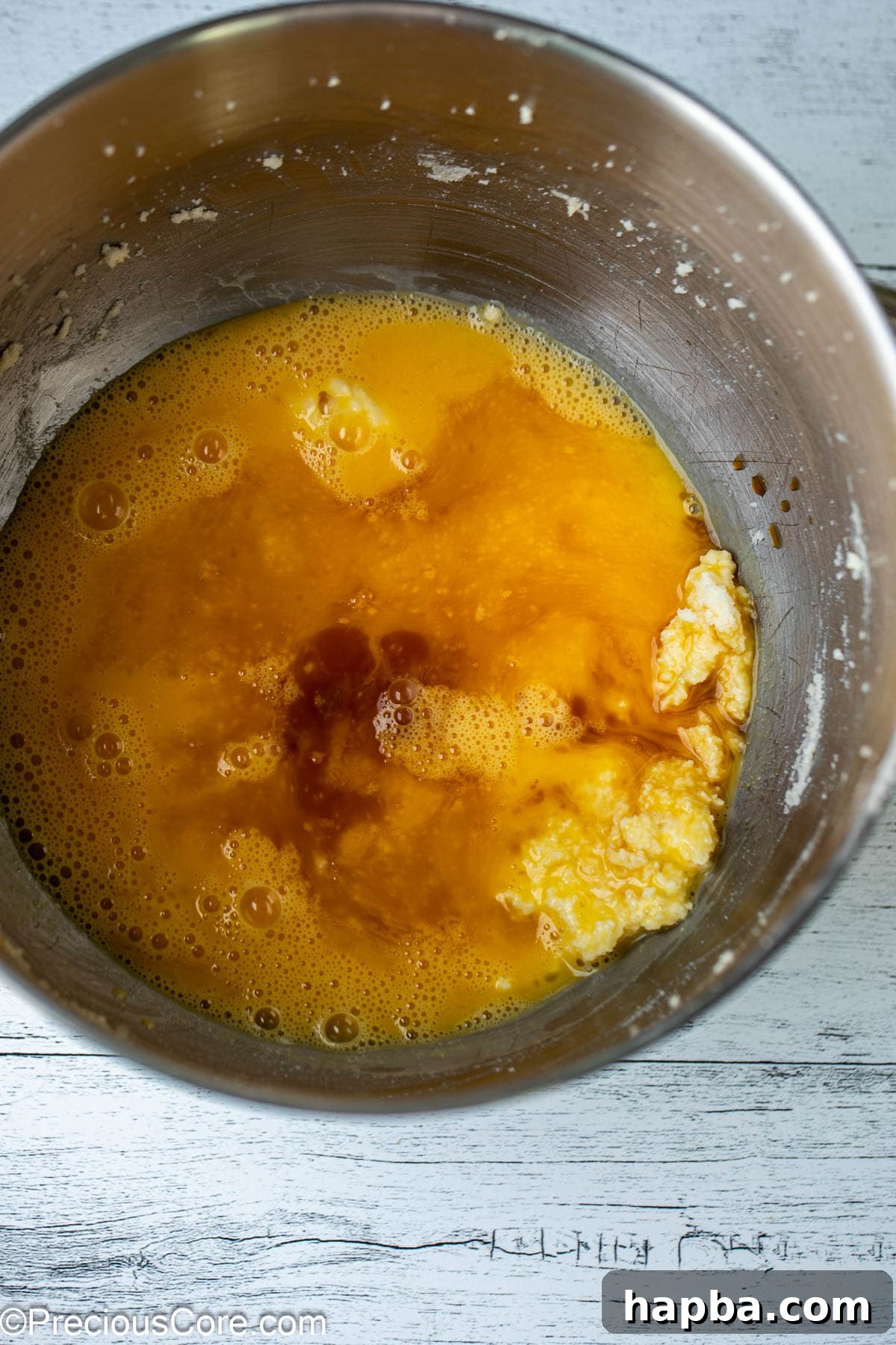 A bowl showcasing wet ingredients – eggs, vanilla extract, and the creamed butter and sugar mixture – ready for the next step.