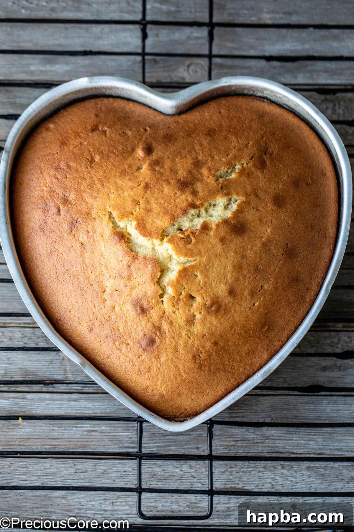 A heart-shaped plain cake cooling on a wire rack, its golden-brown crust promising a tender interior.