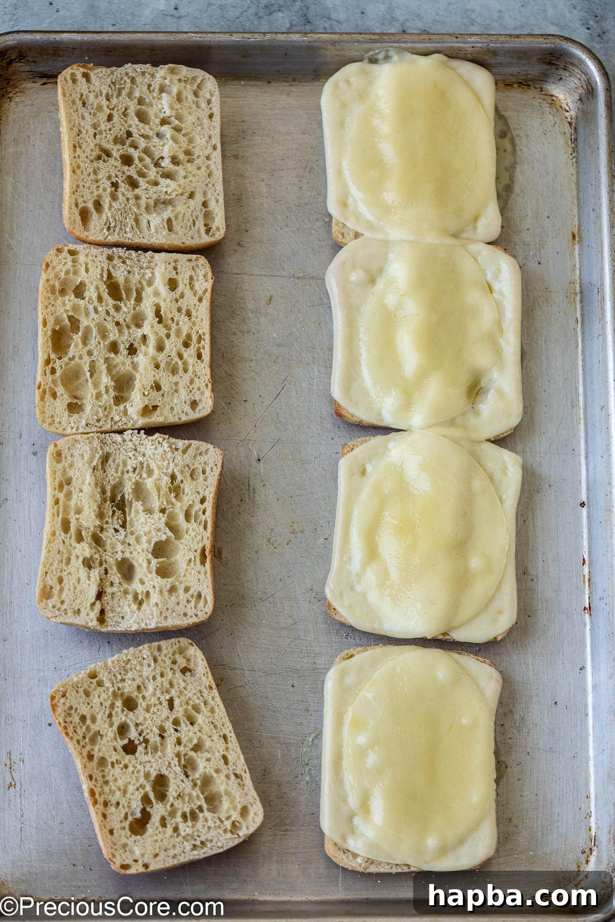 Toasted ciabatta bread halves with golden-brown melted provolone cheese, fresh from the oven.