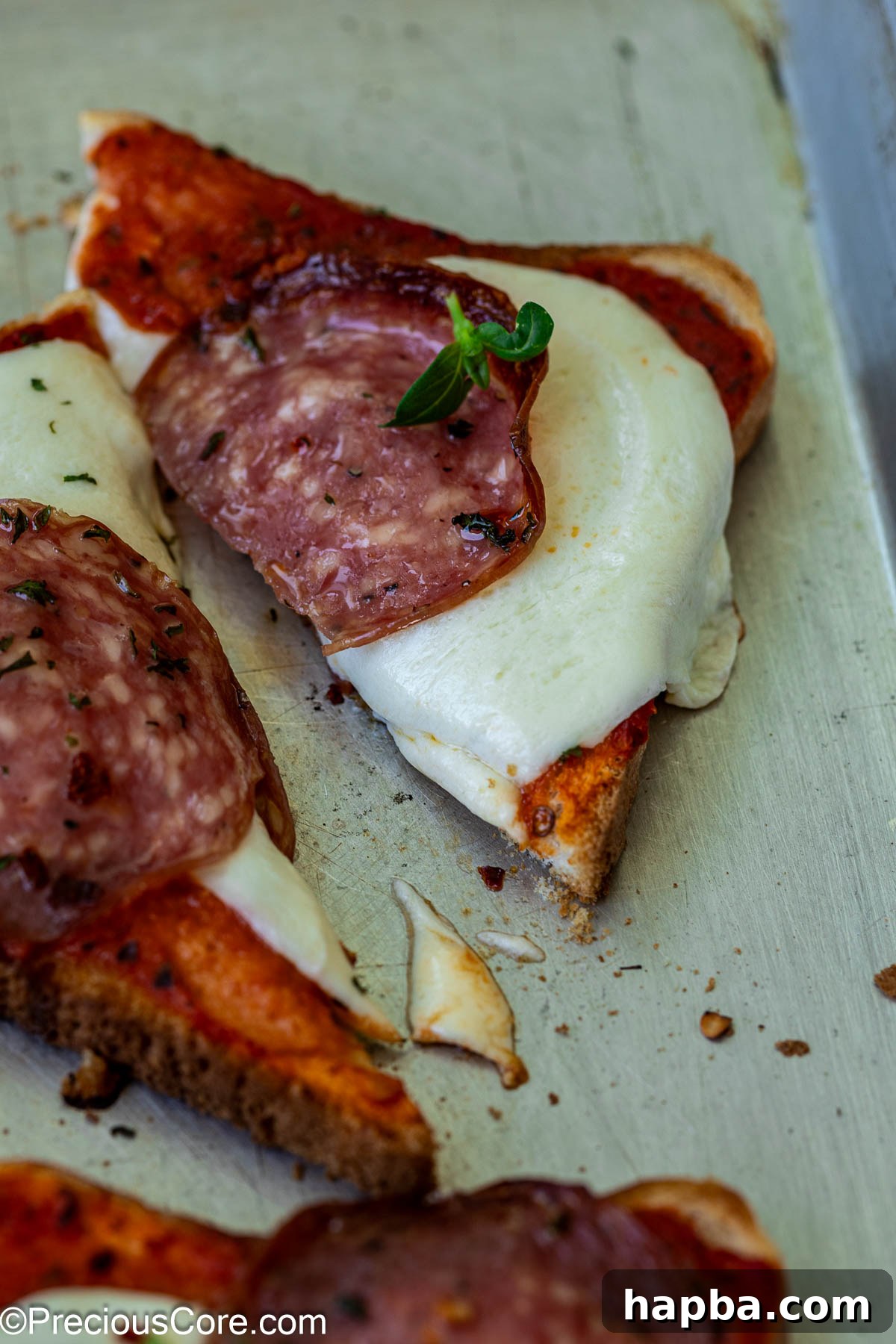 A close-up shot of a pizza toast triangle, showing the perfectly melted cheese and crispy edges, ready to be picked up.