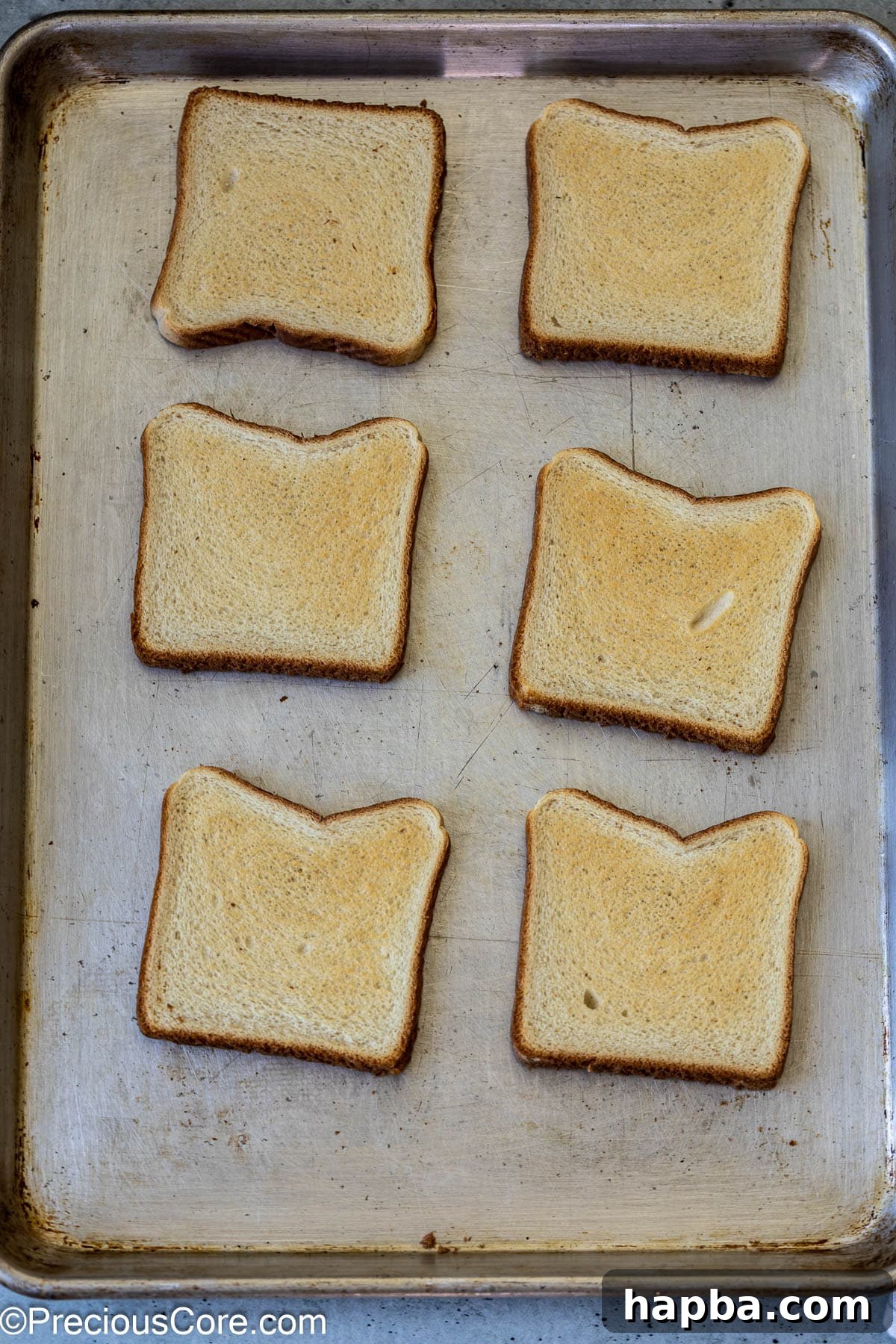Lightly toasted bread slices arranged on a baking sheet, ready for toppings.