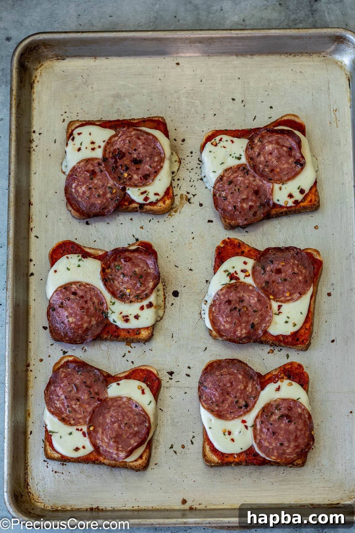 Freshly baked pizza toasts with perfectly melted cheese and toppings, golden and delicious on a baking sheet.