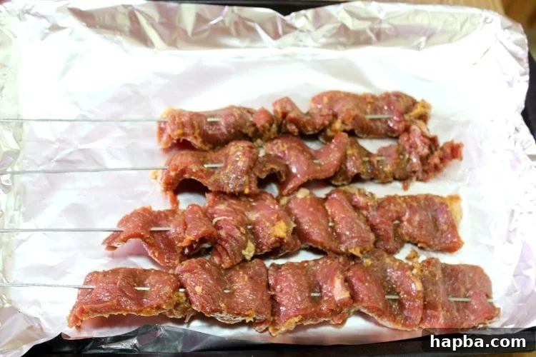 Raw, marinated Cameroonian soya skewers arranged on a lined baking sheet, ready for grilling.