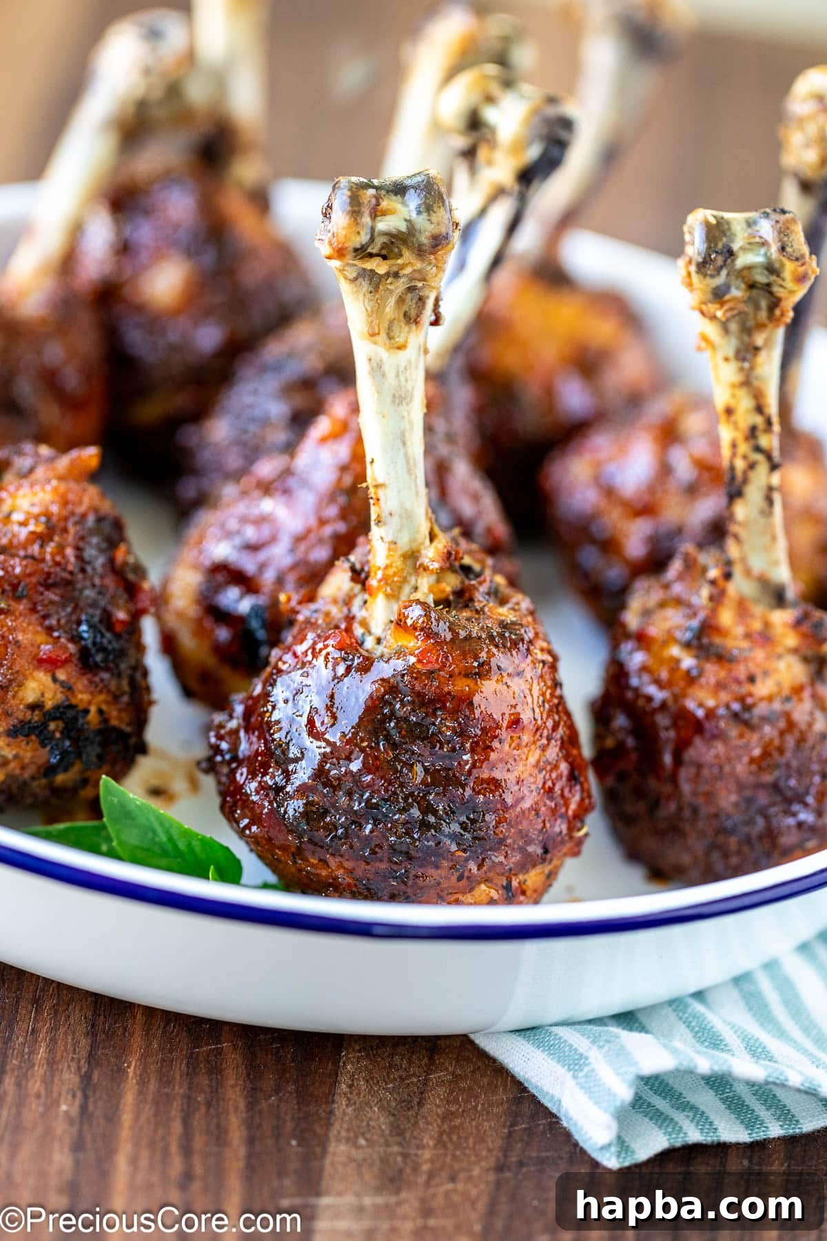 Close-up of perfectly formed baked chicken drumstick lollipops, glistening with glaze.