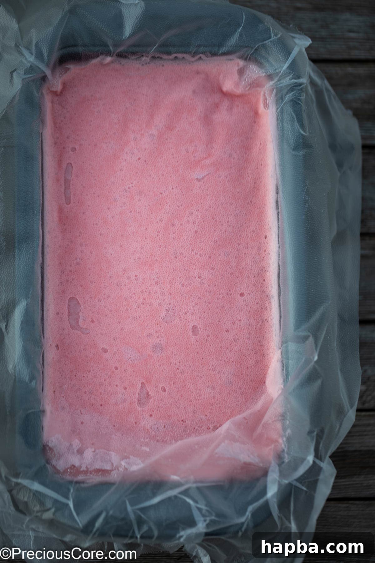 Plastic covering watermelon ice cream mixture.