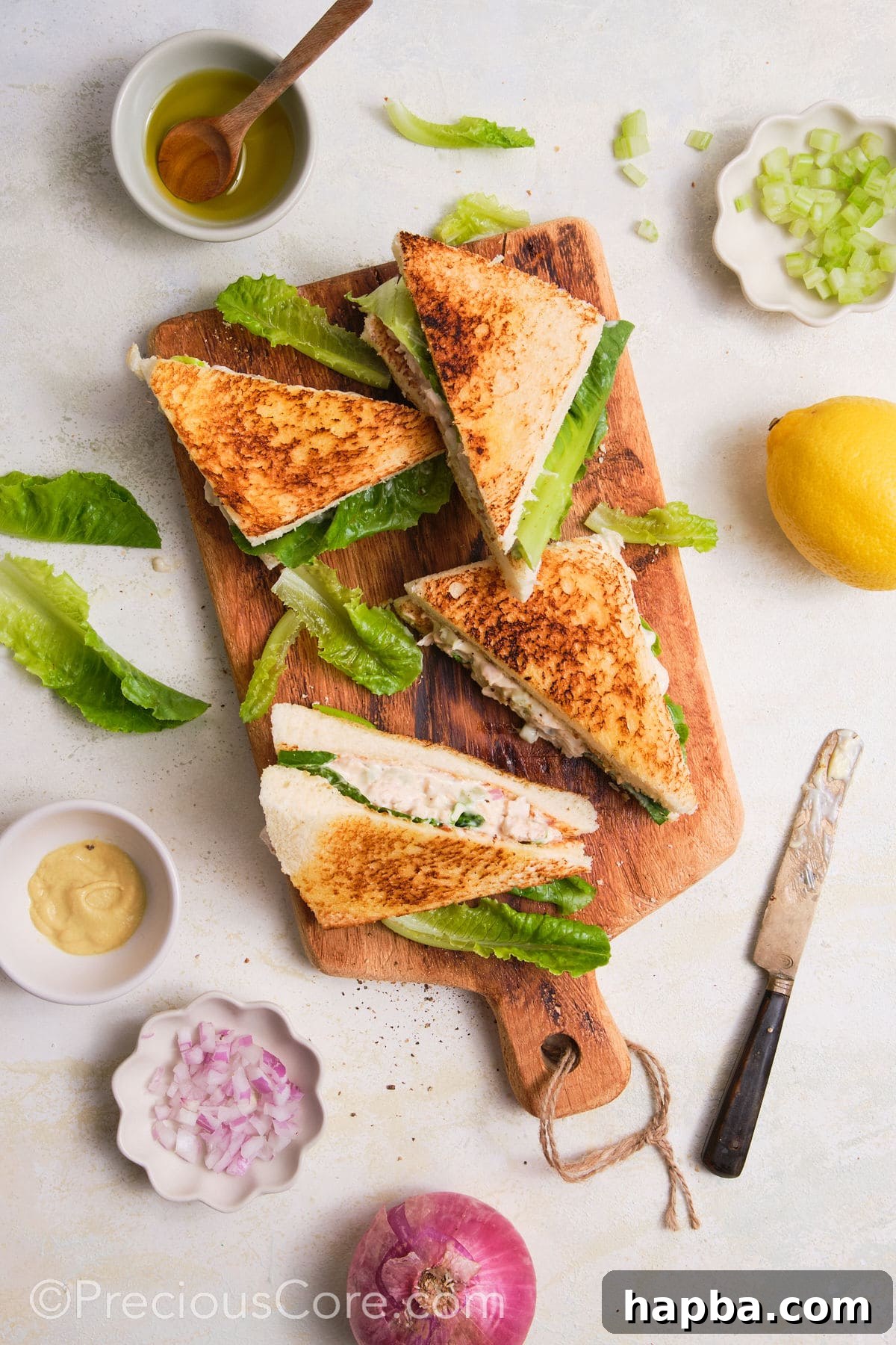 Classic Creamy Chicken Sandwich 3 Freshly cut chicken mayonnaise sandwiches resting on a wooden cutting board, ready to be served.