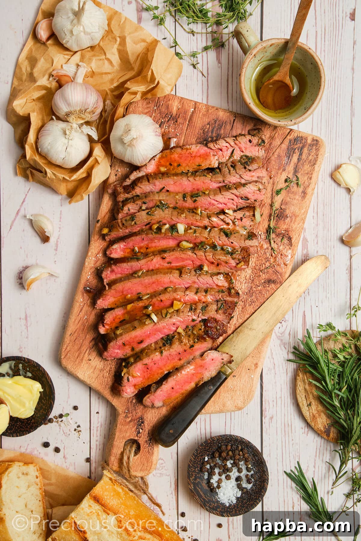 A perfectly cooked flank steak, sliced and surrounded by fresh ingredients like herbs, garlic, and cherry tomatoes, showcasing its versatility.
