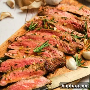 Sliced pan seared flank steak on a cutting board, perfectly cooked.