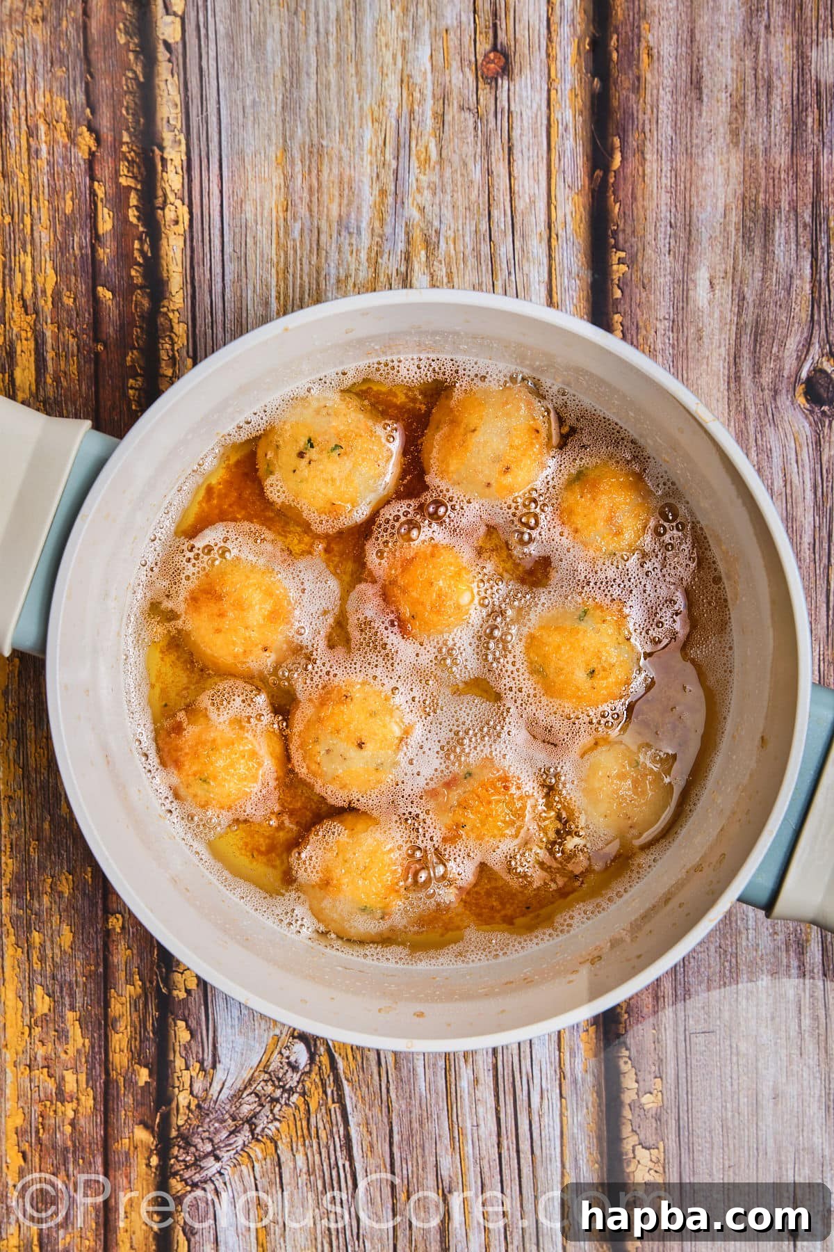 Potato cheese balls deep frying in oil.
