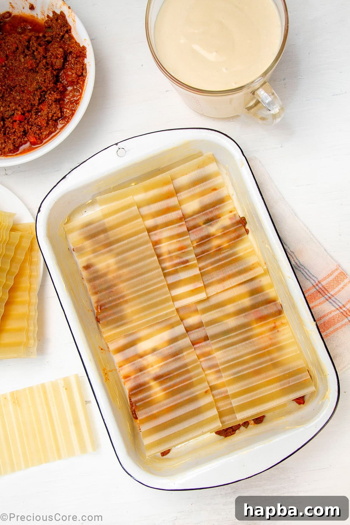 Creamy Béchamel Lasagna 13 No-boil lasagna noodles neatly layered over the meat sauce base in a baking dish, forming the first pasta layer.