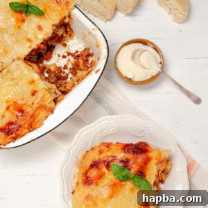 Creamy Béchamel Lasagna 16 A perfectly sliced portion of Lasagna with Béchamel Sauce on a plate, with a freshly baked full dish of lasagna in the background, ready to be served.