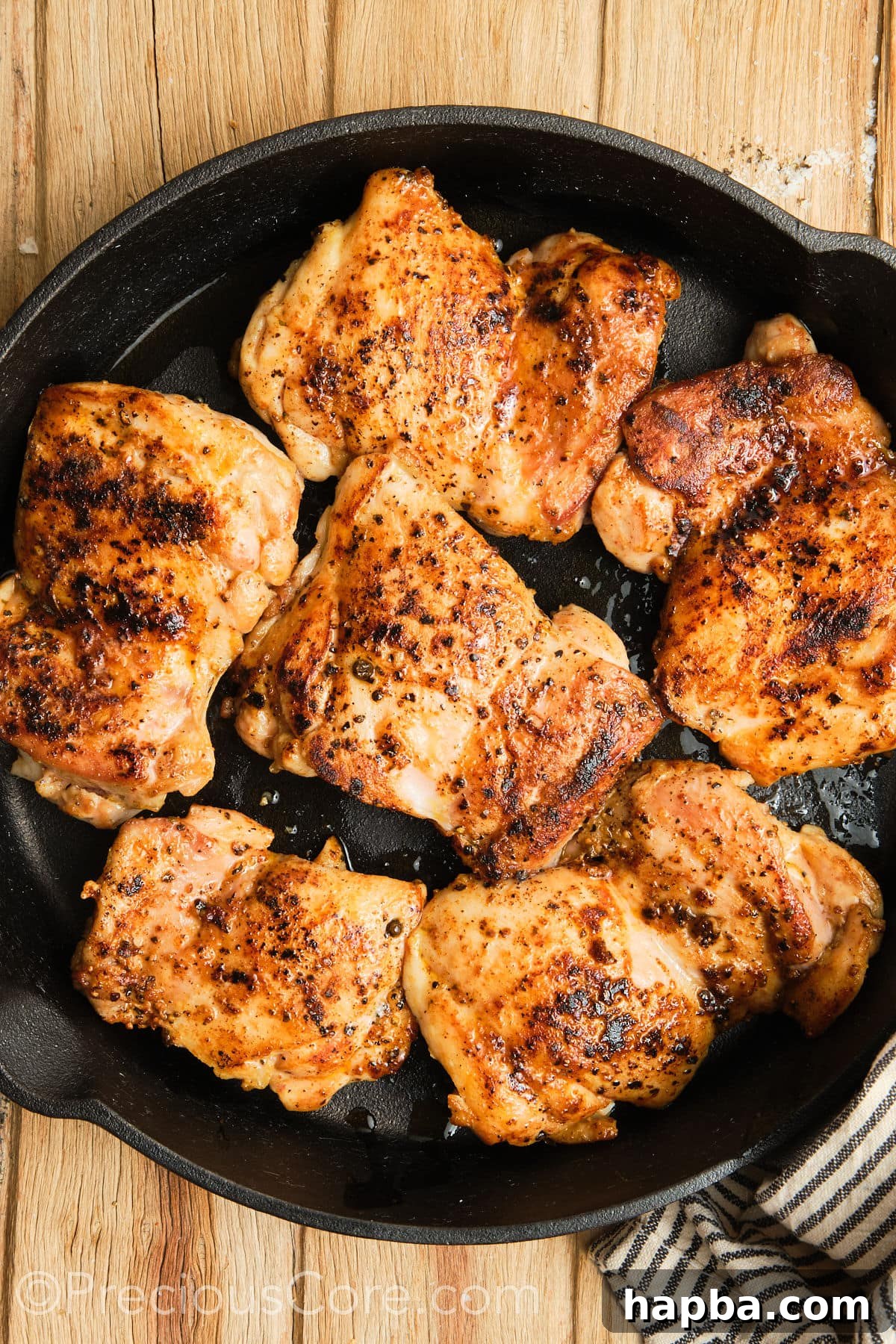Seared boneless chicken thighs in a skillet.