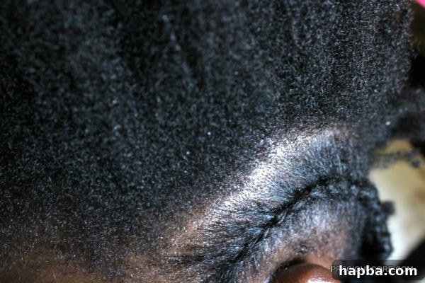 Child's hair sectioned and partially braided into cornrows