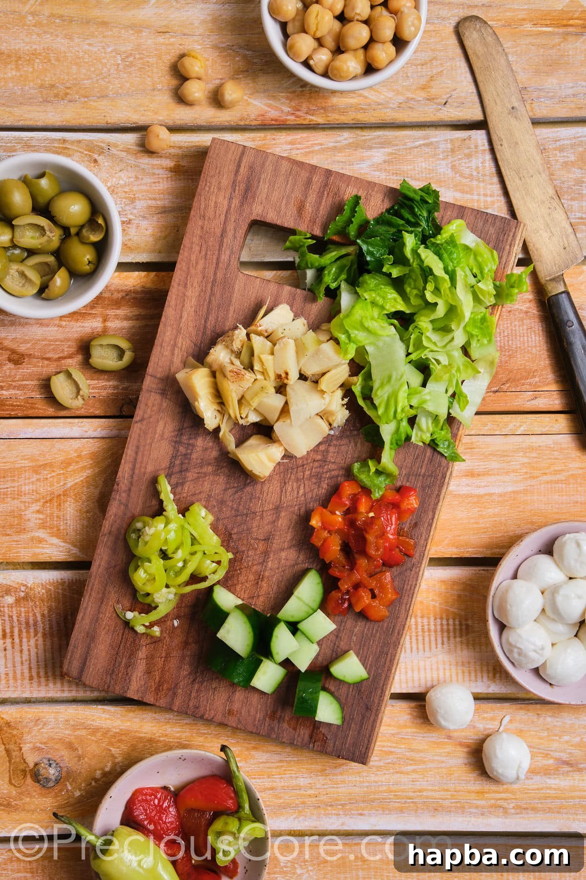 Various diced vegetables, including cucumbers and tomatoes, neatly arranged on a chopping board.