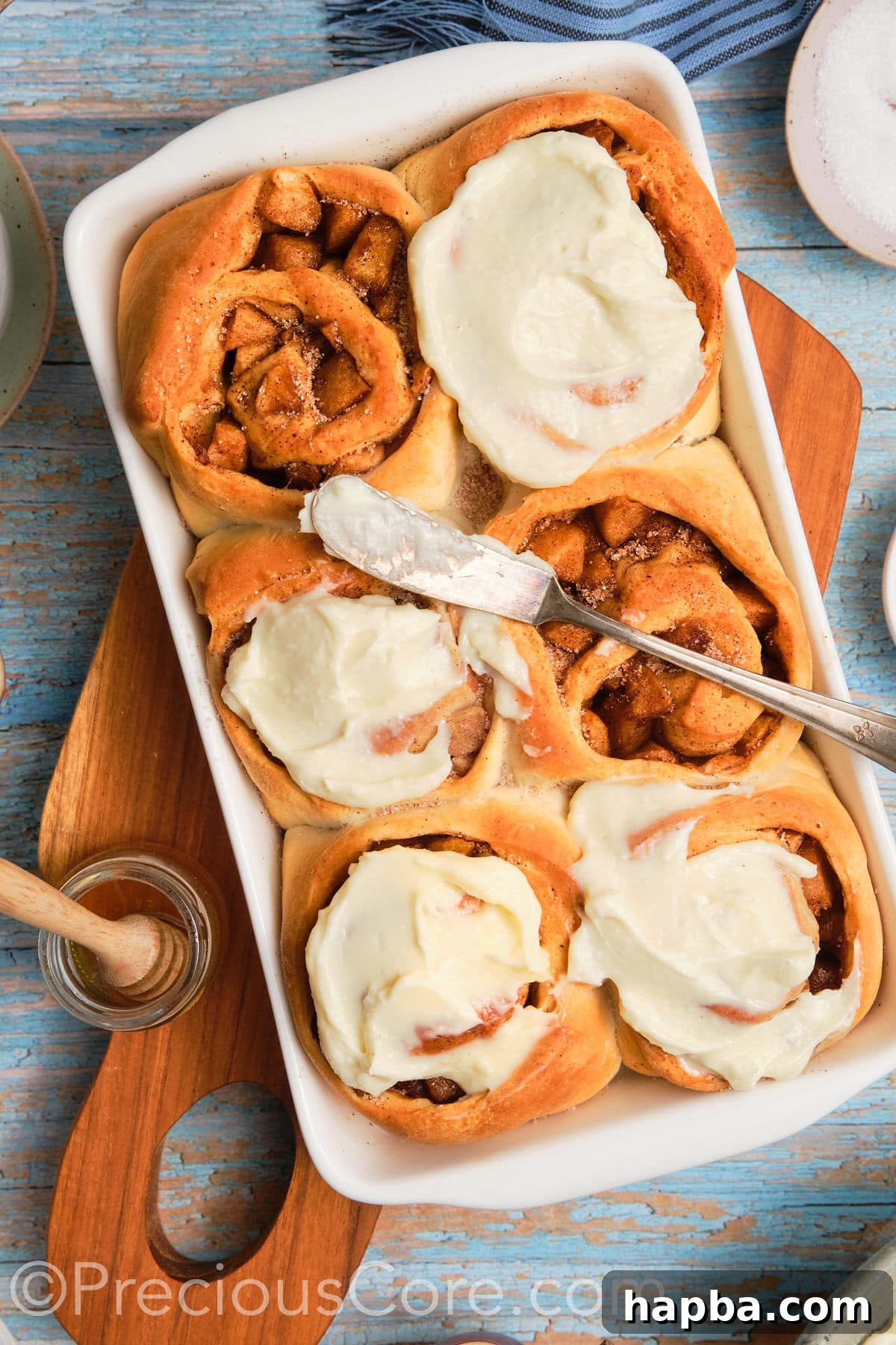 Delicious homemade Cinnamon Rolls filled with apple pie filling, topped with cream cheese frosting, ready to be served.