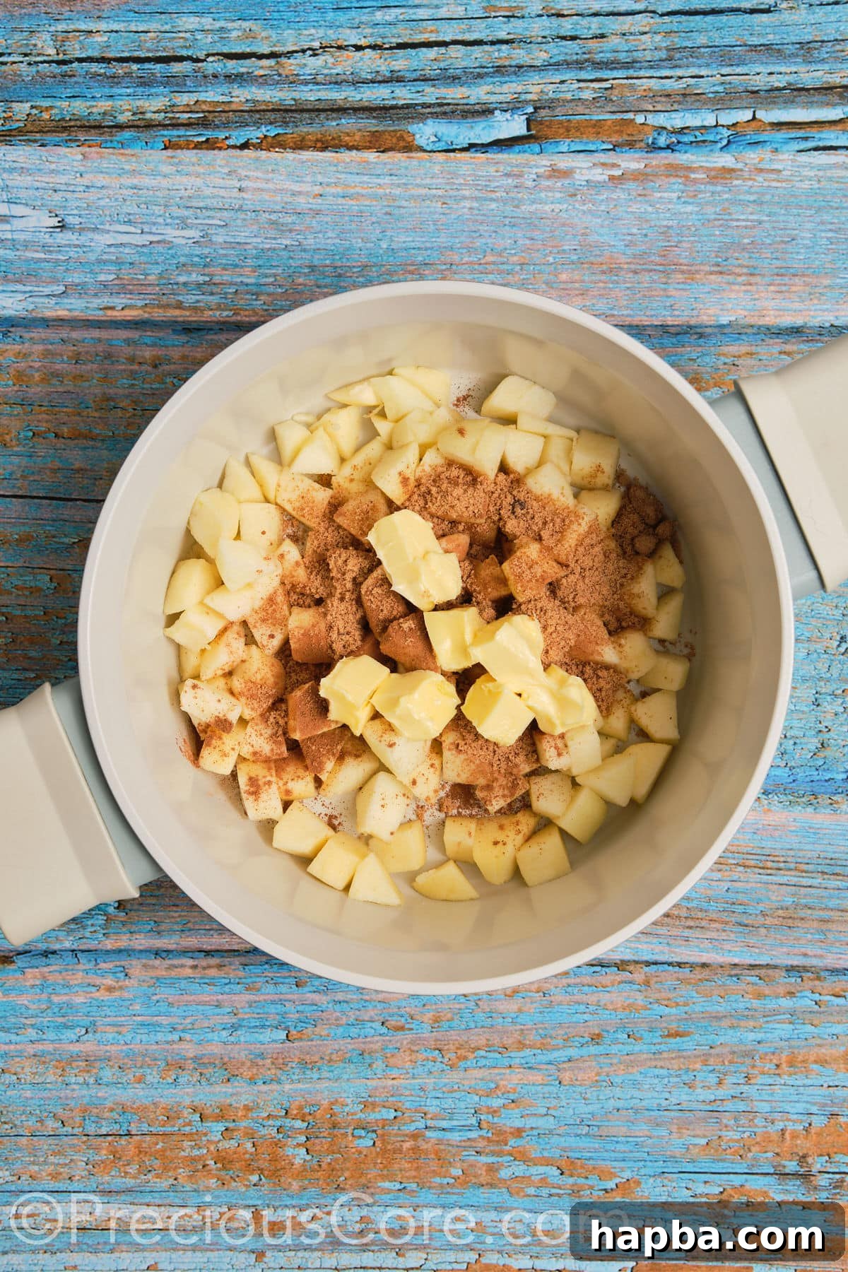 Ingredients for apple pie filling including diced apples, butter, brown sugar, and cinnamon, gathered in a pot ready for cooking.