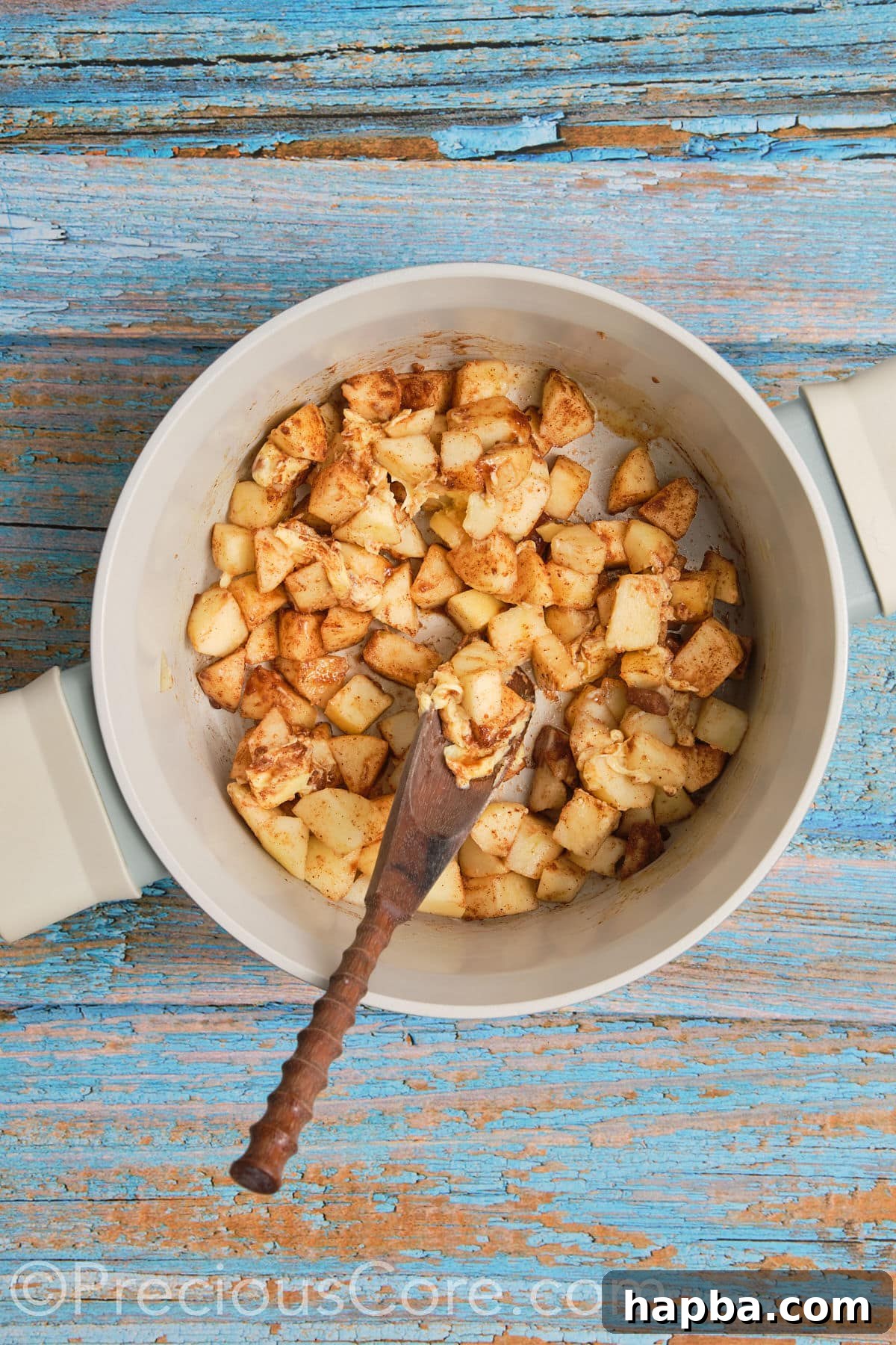 Apple pie filling for cinnamon rolls gently cooking in a pot, apples softening and spices blending.
