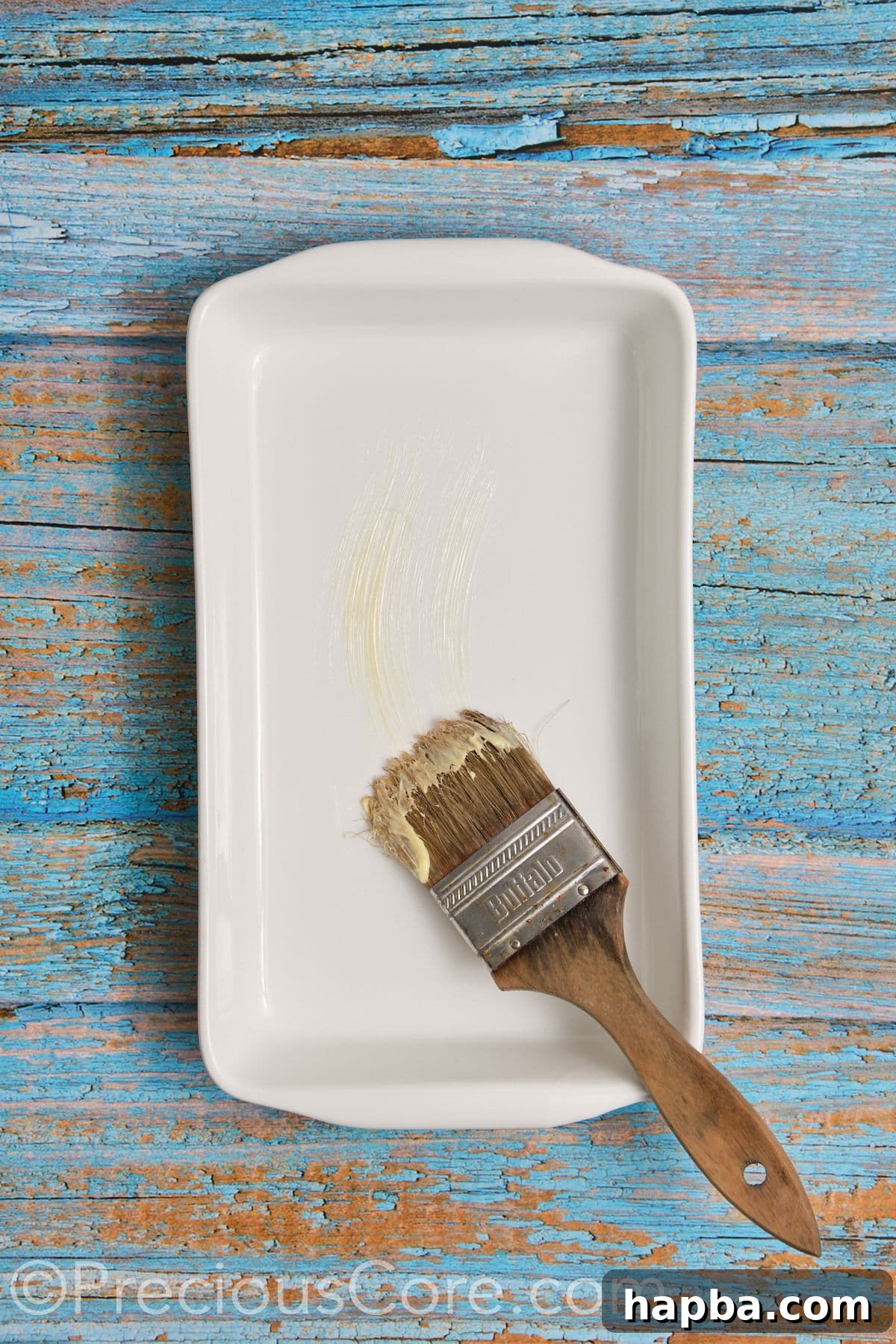 Brushing a casserole dish with softened butter to prepare for the cinnamon rolls.