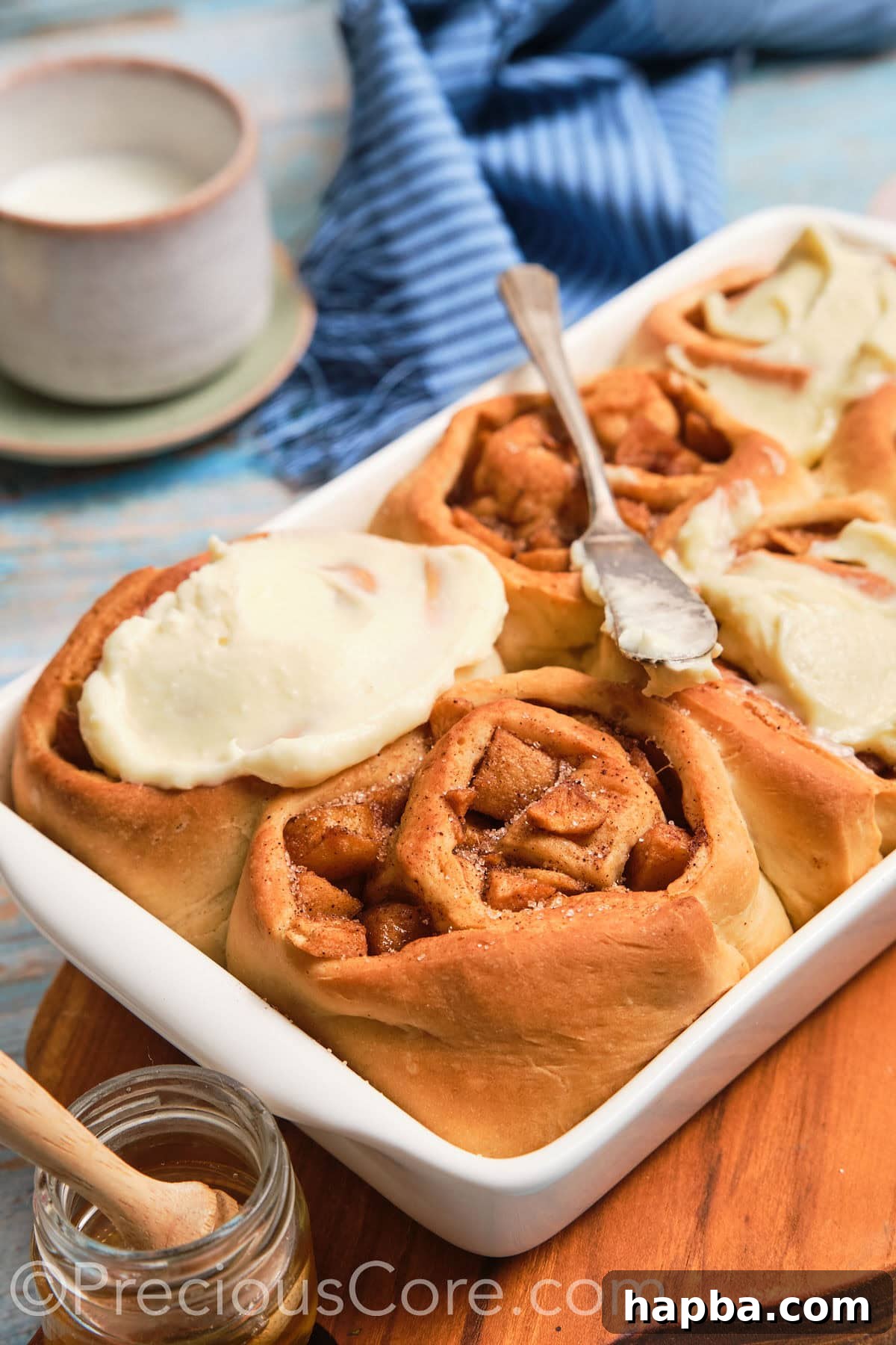 Close-up shot revealing the delicious spiced apple filling inside a freshly baked Cinnamon Roll with cream cheese frosting.
