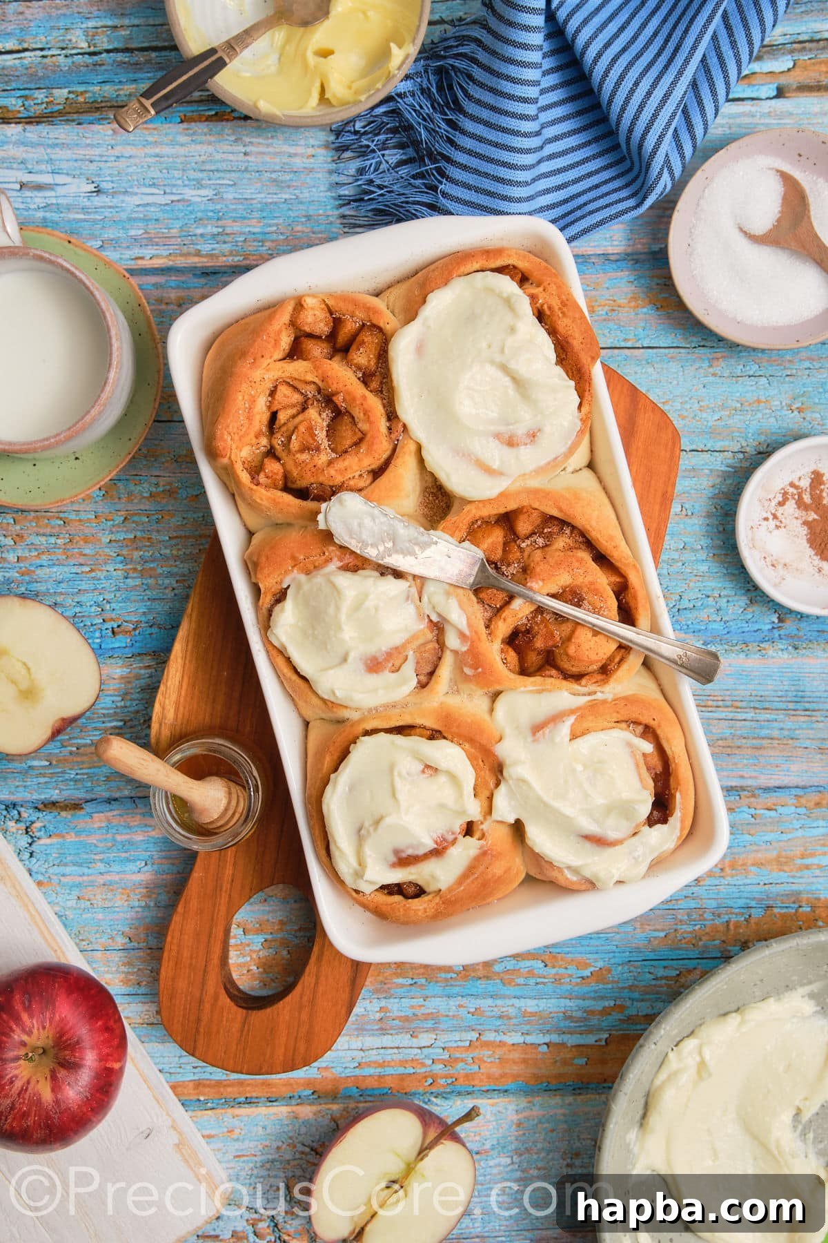 A wide shot of a baking dish filled with beautifully frosted homemade cinnamon rolls with apple pie filling, ready to be enjoyed.