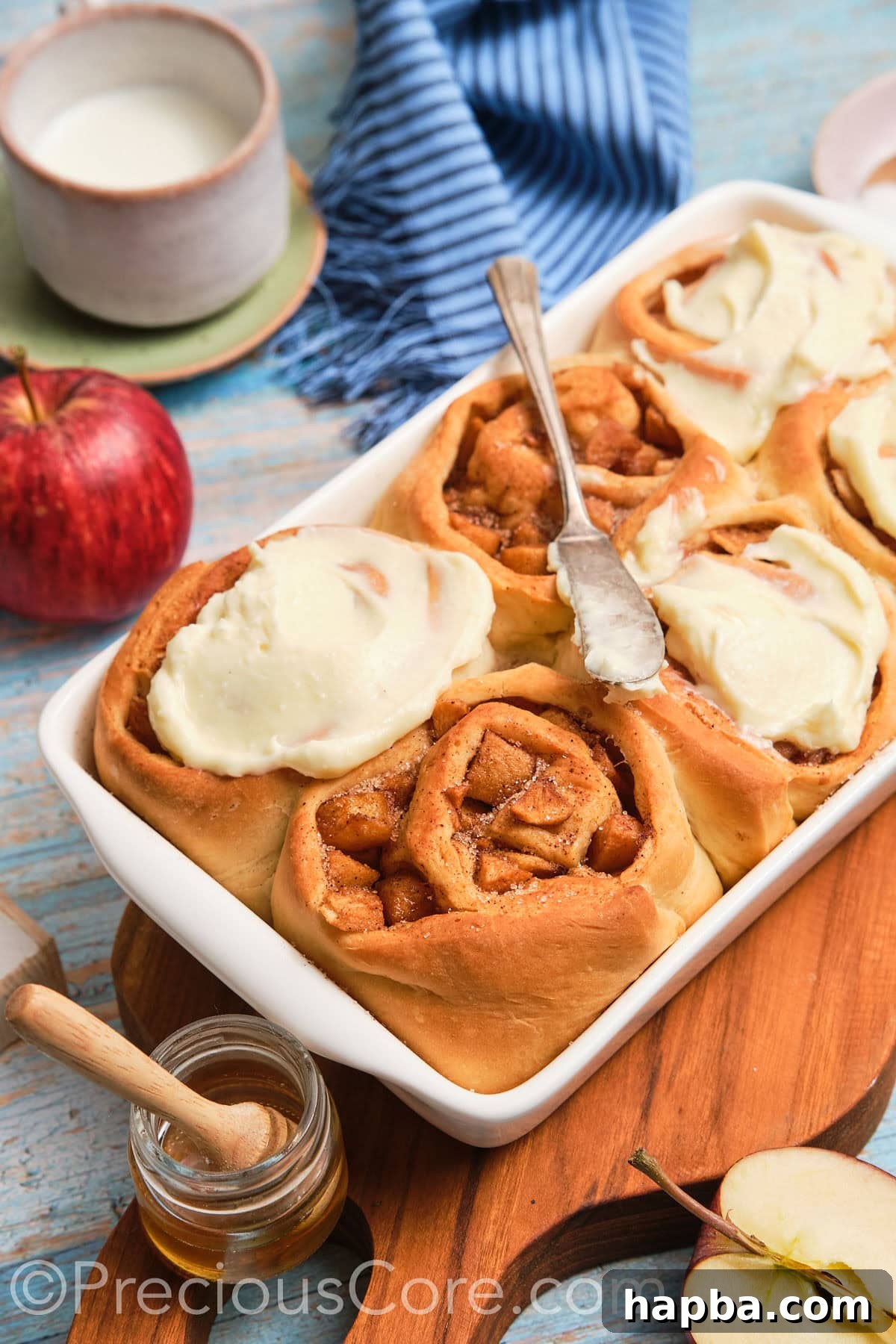 Side view of perfectly baked and frosted homemade apple cinnamon rolls, showcasing their fluffy texture and generous filling.