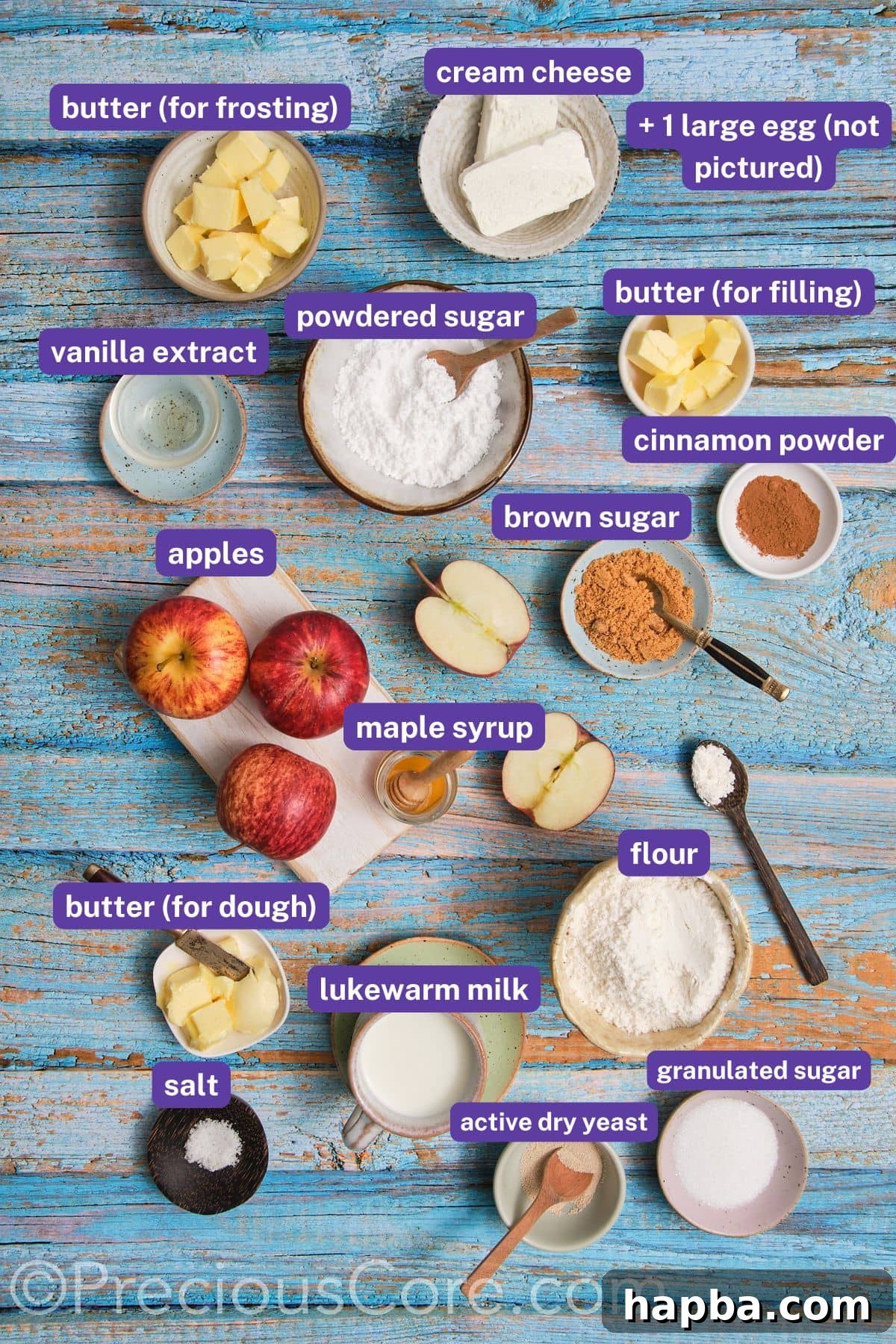 Key ingredients for Apple Pie Cinnamon Rolls, including fresh apples, butter, milk, flour, sugar, and cream cheese, laid out on a surface.