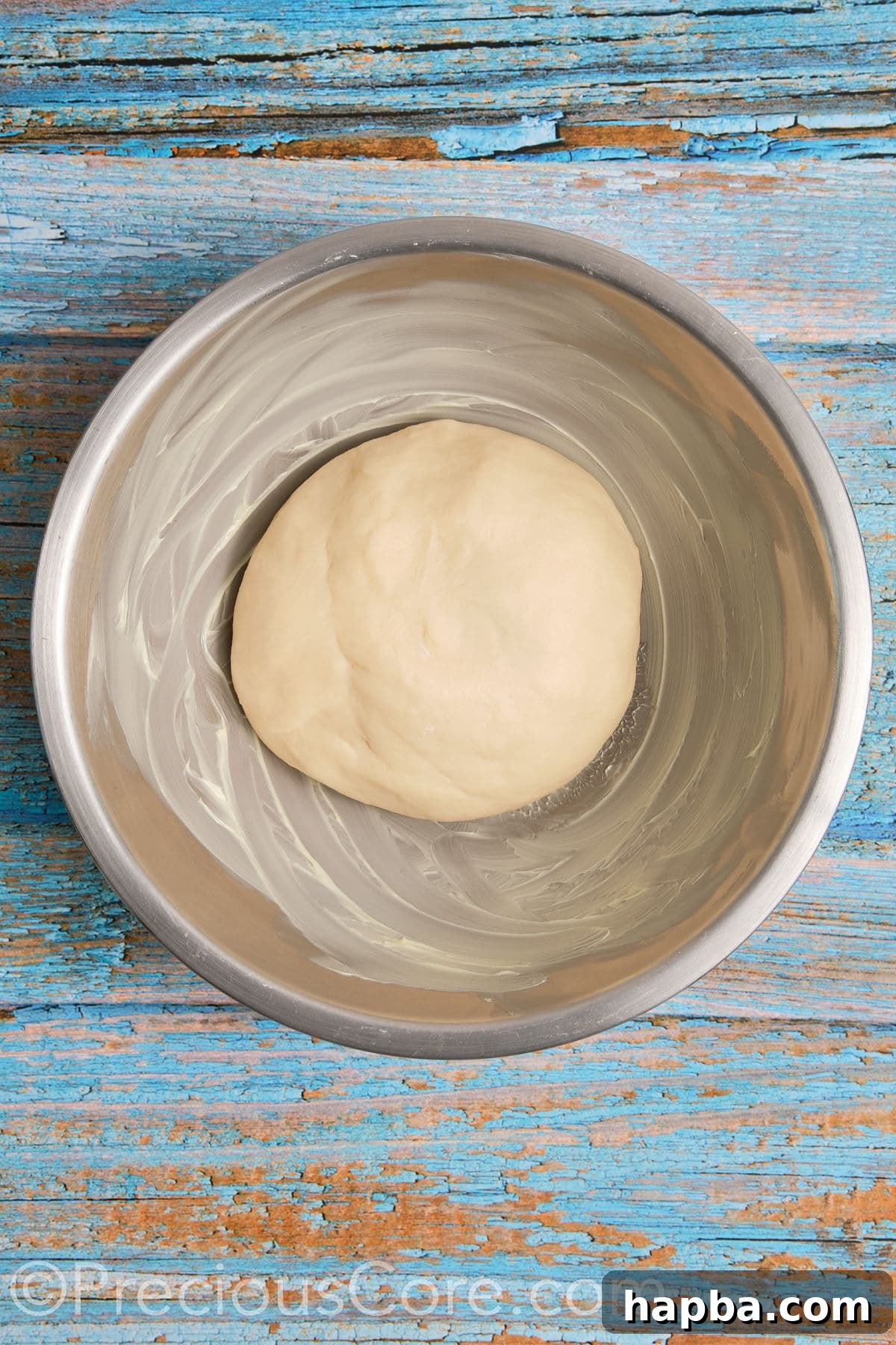 Cinnamon roll dough resting in a buttered bowl, covered for its first rise.