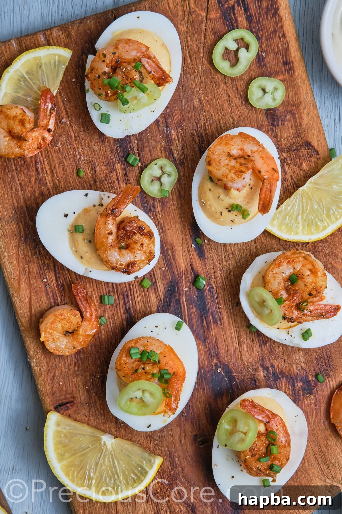 Kickin' Cajun Shrimp Deviled Eggs 2 Deviled eggs with shrimp on a chopping board.