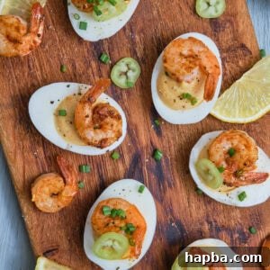 Kickin' Cajun Shrimp Deviled Eggs 25 Deviled eggs with Cajun shrimp on a chopping board.