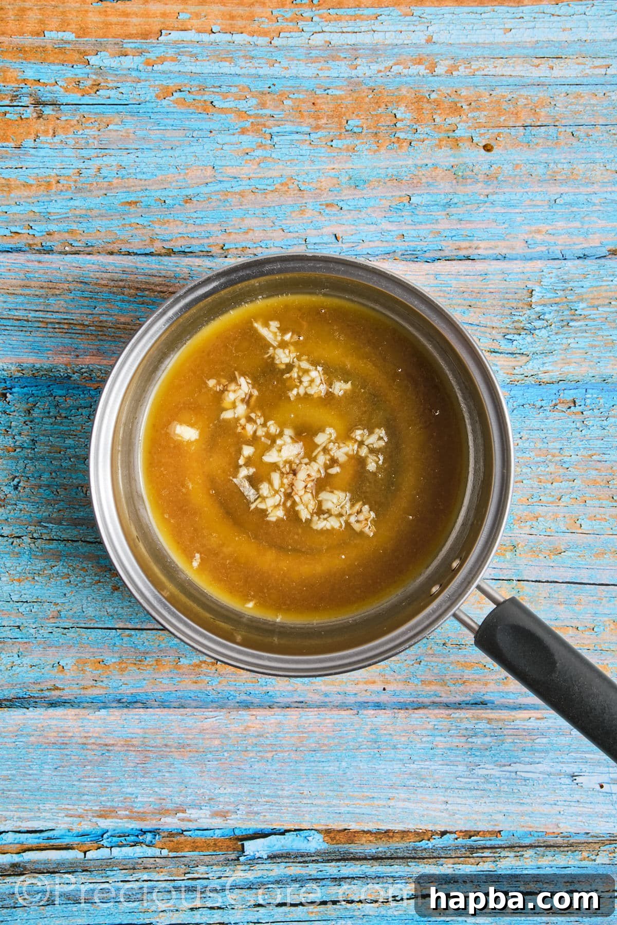 Ingredients for honey butter sauce melting and mixing in a small saucepan over medium heat.
