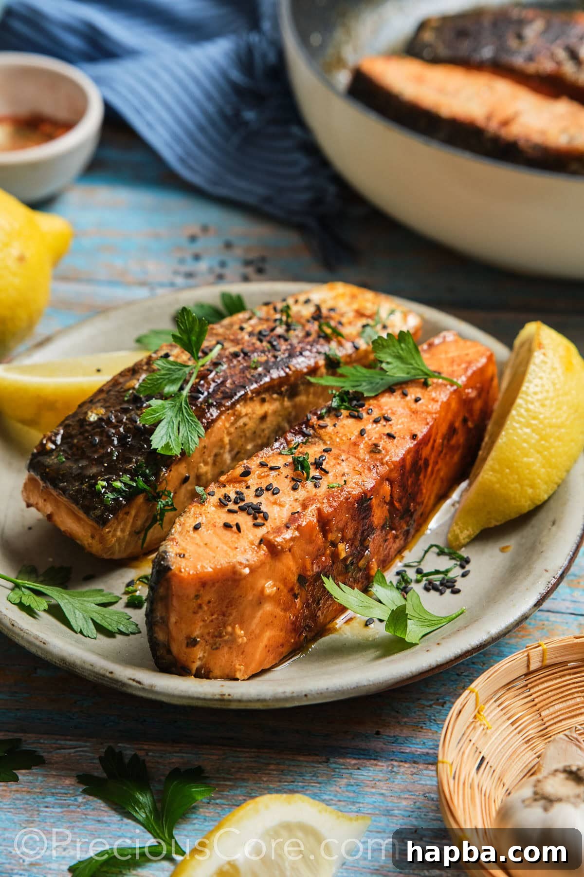 Two cooked Cajun Honey Butter Salmon fillets, garnished with black sesame seeds and fresh herbs, ready to be served.