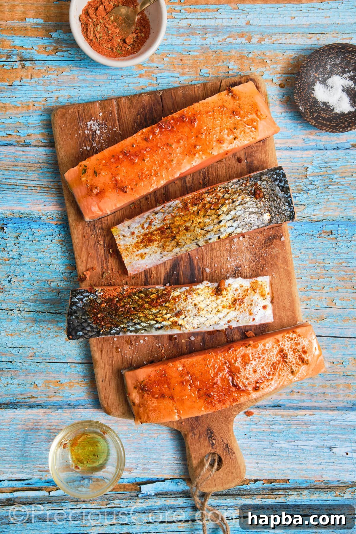 Salmon fillets generously coated with Cajun seasoning and olive oil on a cutting board.