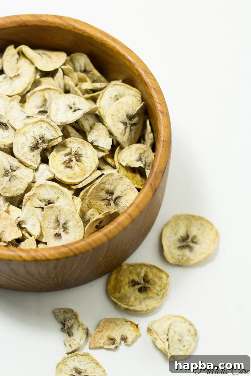 Wooden bowl filled with thin slices of dried plantains, ready for grinding.