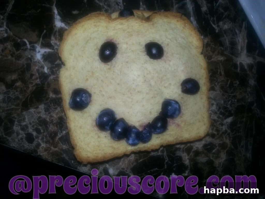 A creative face made on bread with blueberries, a fun breakfast idea for kids.