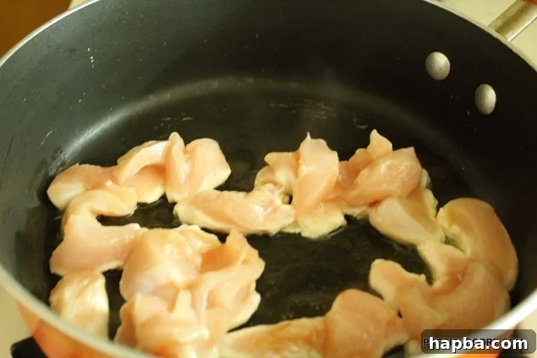Chicken strips frying in hot olive oil in a pot