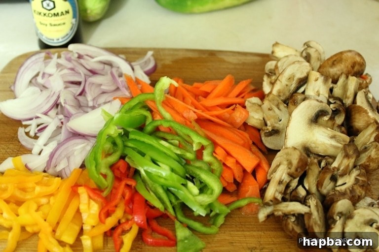 Assorted vegetables including bell peppers, onions, carrots, and mushrooms, chopped and ready for stir frying