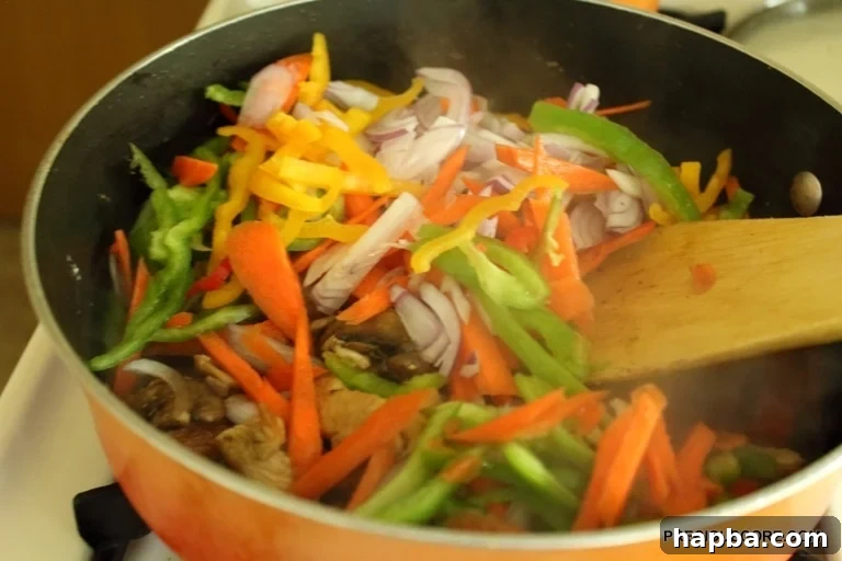 All chopped vegetables, including bell peppers, carrots, and onions, added to the stir fry with chicken and mushrooms