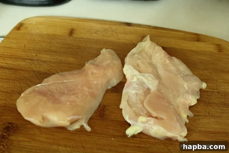 Two boneless, skinless chicken breasts on a cutting board, ready for stir fry preparation
