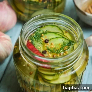 Speedy Zesty Pickles 12 Quick pickled cucumbers in a mason jar with peppercorns on top.
