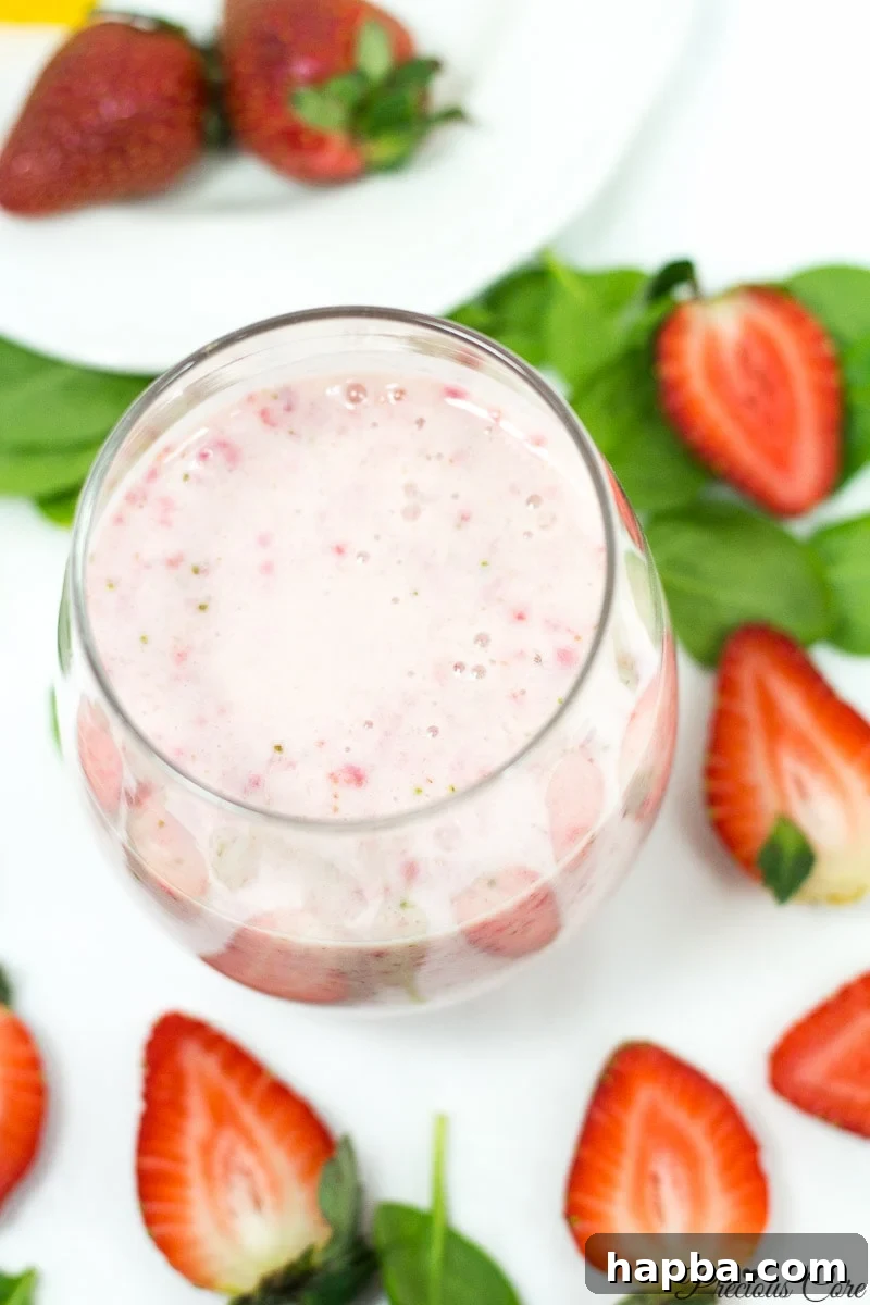 A delightful strawberry banana smoothie in a small clear glass, showcasing its creamy texture and pink color, a perfect blend of sweet fruits.