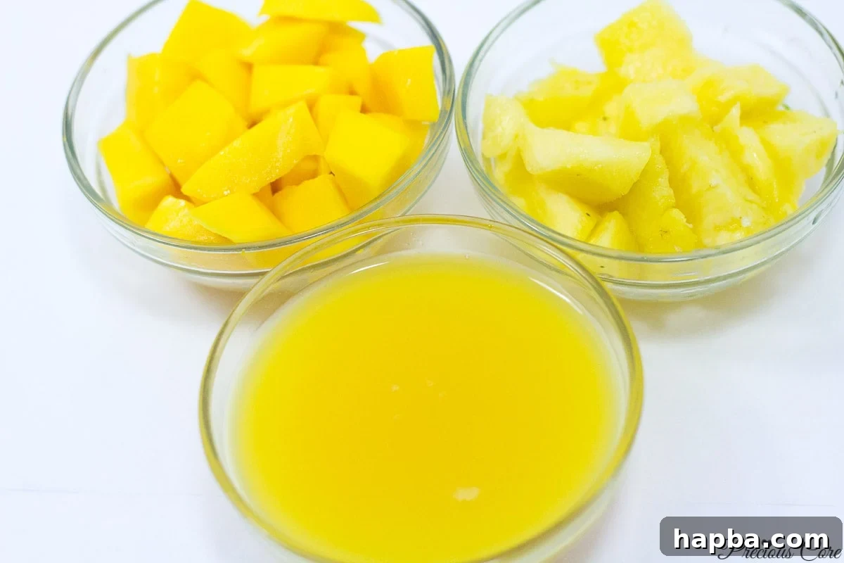 Individual bowls containing fresh pineapple chunks, ripe mango slices, and a glass of 100% orange juice, neatly arranged as ingredients for a tropical smoothie.