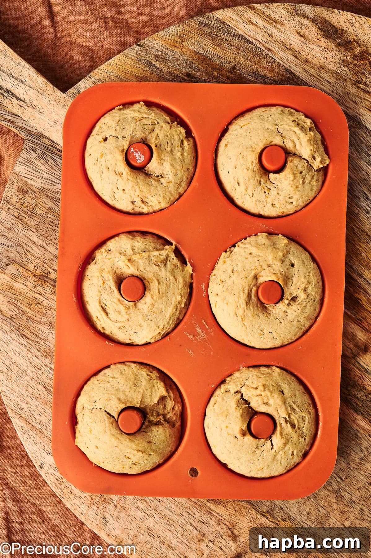 Freshly baked pumpkin spice doughnuts in the doughnut pan, golden brown and puffed up.