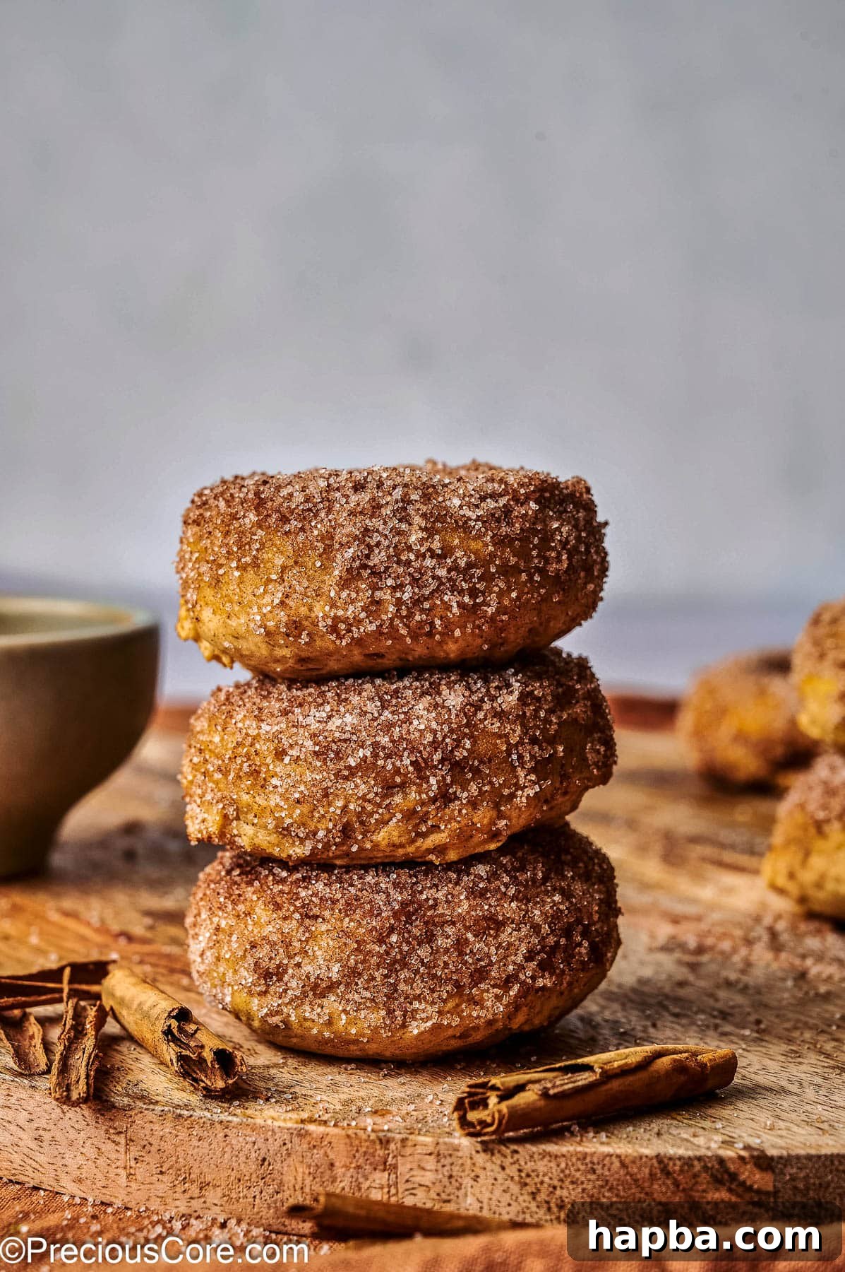 Close-up of baked pumpkin spice doughnuts beautifully stacked, emphasizing their soft texture and appealing coating.