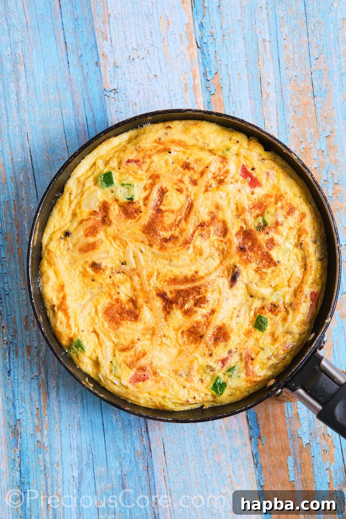 The spaghetti omelette expertly flipped in the skillet, showcasing its beautifully cooked surface.