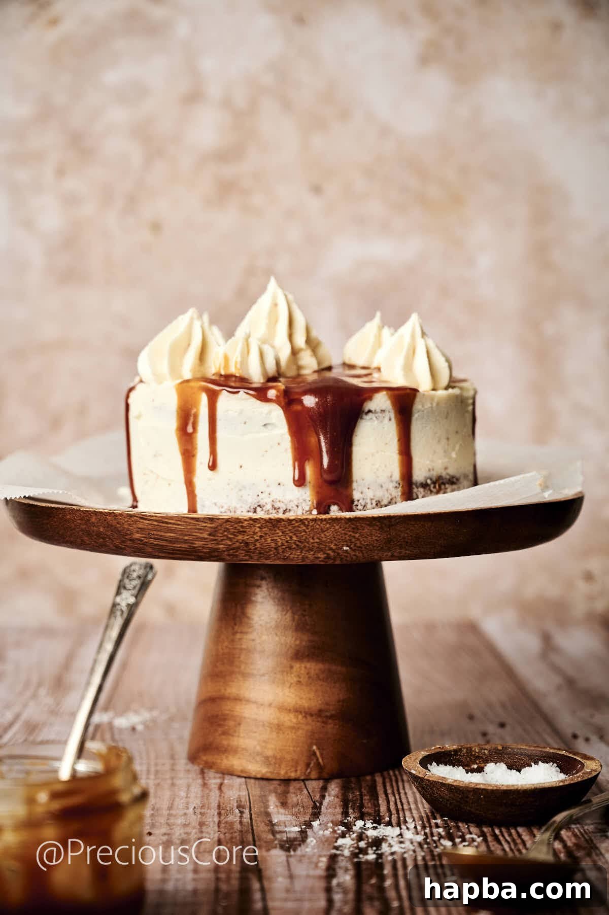 Salted Caramel Dream Cake 5 A stunning multi-layered cake coated in smooth white frosting, adorned with elegant caramel drips along its sides, resting on a sophisticated cake stand.