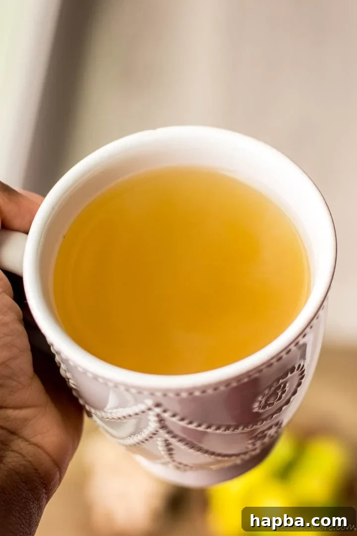 A hand holding a steaming mug of ginger tea, inviting the viewer to experience its warmth and comfort.